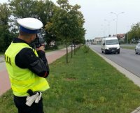Policjant ruchu drogowego dokonuje pomiaru prędkości jadących samochodów