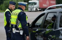 Policjanci w umundurowaniu służbowym kontrolują samochód osobowy