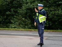 Policjant w umundurowaniu służbowym kieruje ruchem