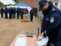 Komendant Miejski Policji w Suwałkach zwija akt erekcyjny, w tle policjanci i zaproszeni goście