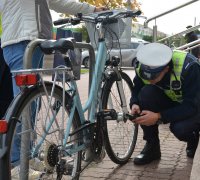 Policjanci w umundurowaniu służbowym sprawdzają rower