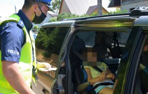 Policjant sprawdza przewożenie dziecka w samochodzie