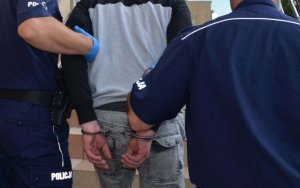 Policjanci prowadzą mężczyznę skutego w kajdankach