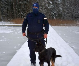 Policjant z psem służbowy podczas patrolu w pobliżu  jeziora w śnieżnej scenerii