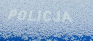 napis POLICJA przyprószony śniegiem