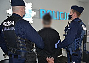 Policjanci w umundurowaniu ćwiczebnym doprowadzają zatrzymanego